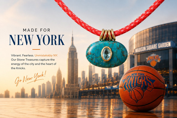 Necklace with blue stone pendant and red cord in front of New York cityscape, including Empire State Building and Madison Square Garden.