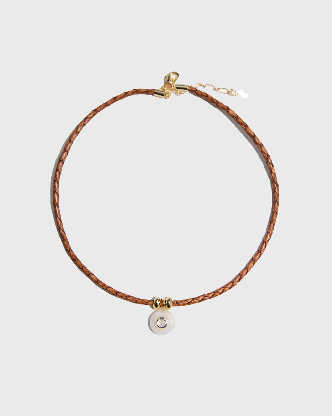 Brown braided leather necklace with a round pendant on a light gray background