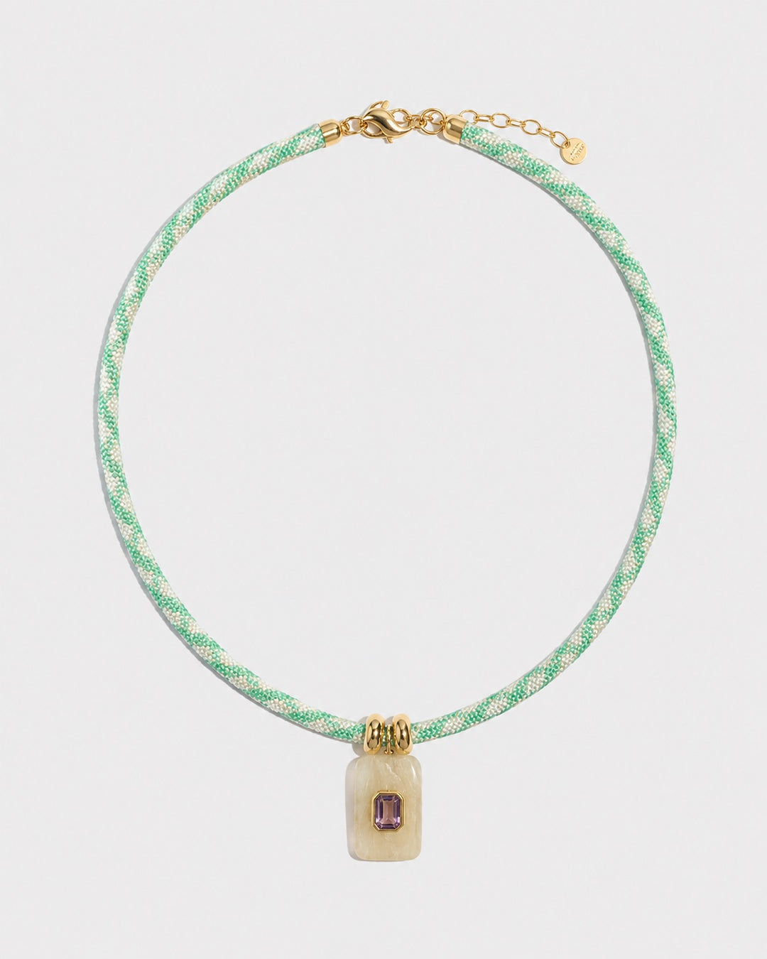 Necklace with green rope and gold clasp on a light grey background