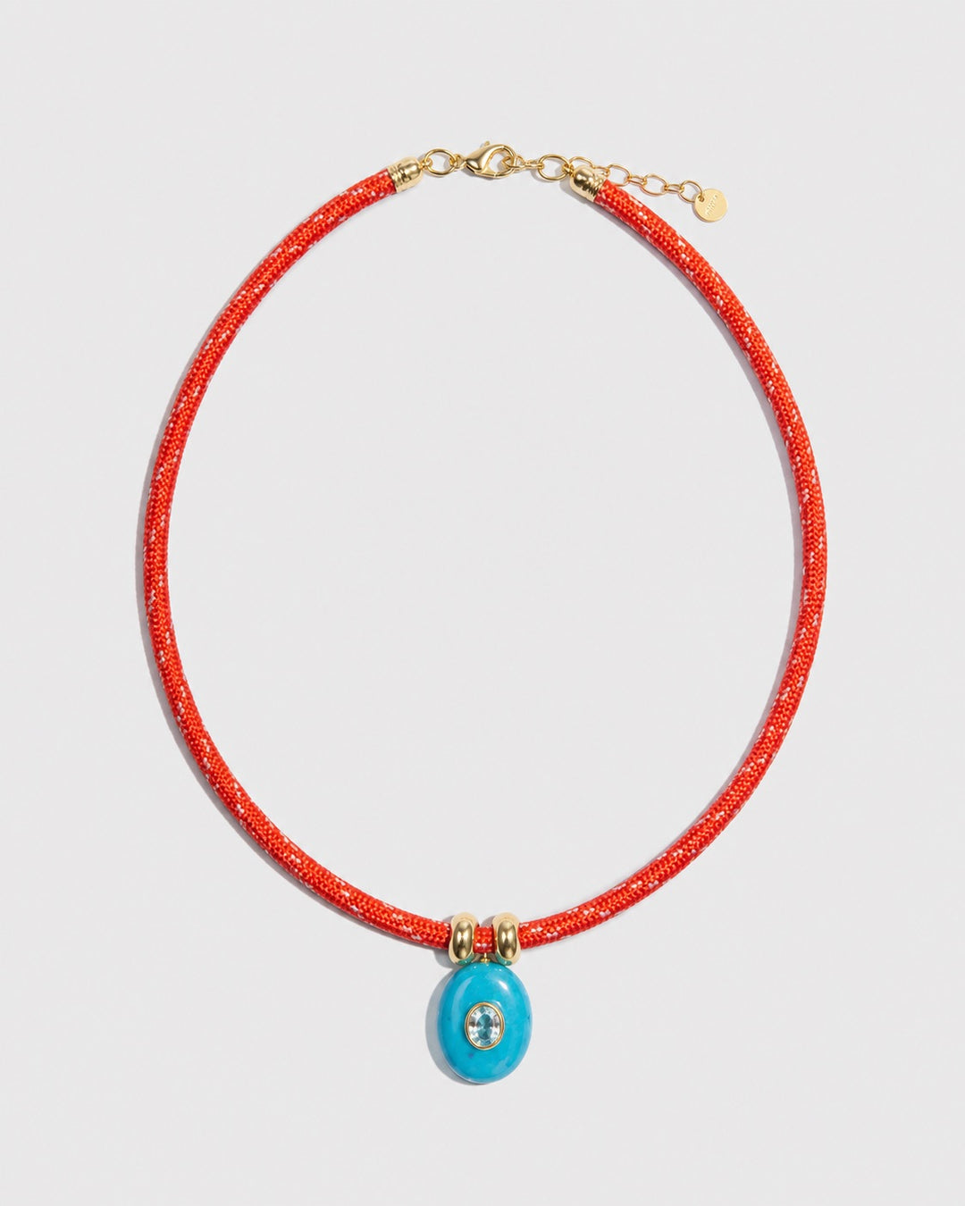 Necklace with red cord and blue pendant on a light gray background