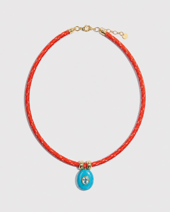 Necklace with red cord and blue pendant on a light gray background