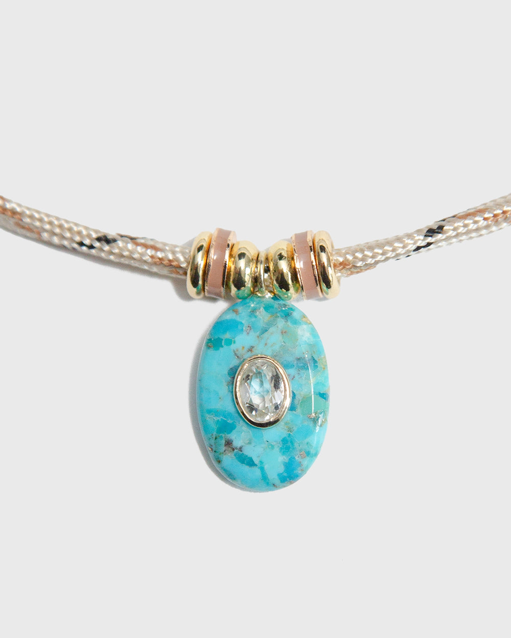 Turquoise bead with gold accents on a light gray background