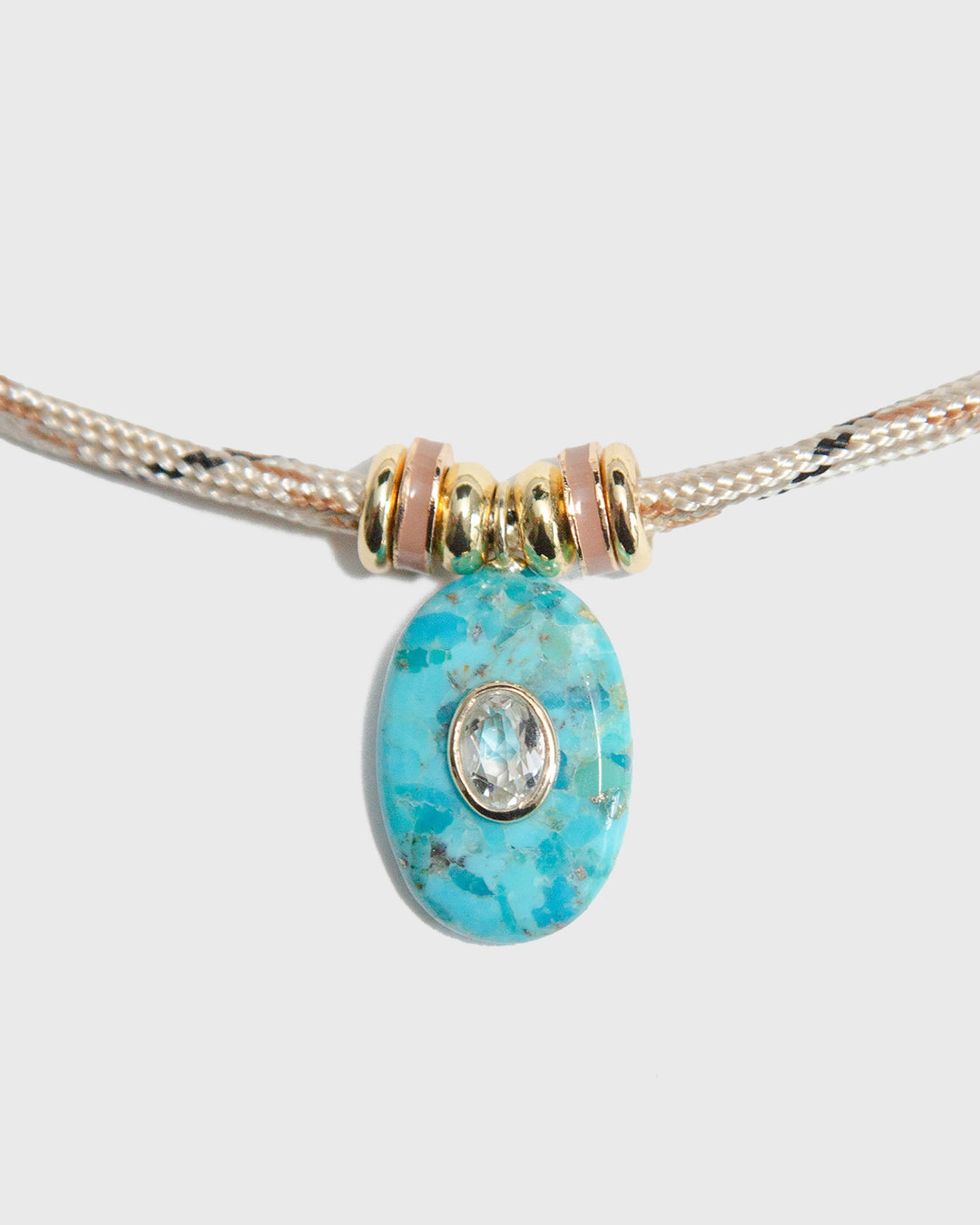 Turquoise bead with gold accents on a light gray background