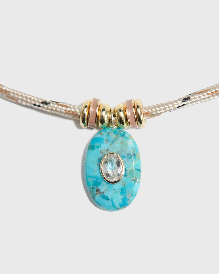 Turquoise bead with gold accents on a light gray background